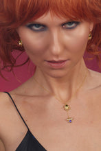 Load image into Gallery viewer, Woman with red hair wearing a gold necklace with a pendant against a pink background