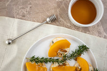 Load image into Gallery viewer, Plated dish with orange slices, rosemary, and walnuts next to a small bowl of honey on a textured surface with a honey dipper.