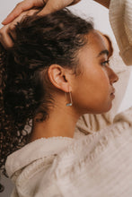 Load image into Gallery viewer, Woman with styled hair and earrings, wearing a light-colored top.