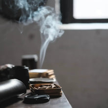 Load image into Gallery viewer, Smoking activity with smoke rising from a pipe on a wooden surface.