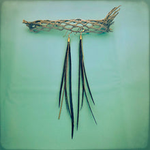 Load image into Gallery viewer, Black coque feather and gold chains hang from a gold earwire hang from natural material