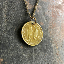 Load image into Gallery viewer, Gold coin pendant necklace on a textured stone surface
