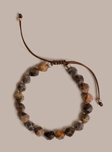 Load image into Gallery viewer, A beaded adjustable cord bracelet featuring faceted brown, beige, and gray stone beads, accented with small silver spacer beads, on a solid taupe background.