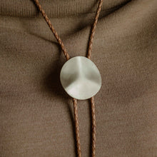 Load image into Gallery viewer, A person wearing a beige off-shoulder sweater with a brass bolo tie featuring a braided genuine leather cord.