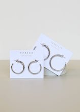 Load image into Gallery viewer, Two pairs of silver hoop earrings on a 'JaxKelly' branded cards