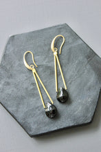 Load image into Gallery viewer, Gold earrings with black gemstones on a gray stone surface