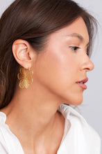 Load image into Gallery viewer, Close-up of a woman wearing gold floral earrings against a neutral background