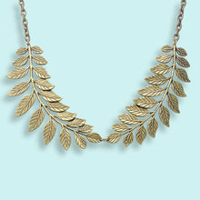 Load image into Gallery viewer, Gold leaf necklace on a light blue background