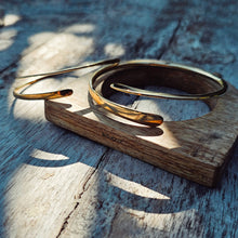Load image into Gallery viewer, Gold bracelet on a wooden stand with a natural wood background