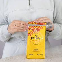 Load image into Gallery viewer, Person opening a Gevalia coffee package with a knife on a neutral background