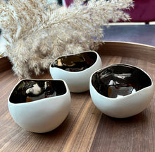 Load image into Gallery viewer, A set of three ceramic candle holders with a bronze interior and a muted beige exterior finish on a wood surface with dried flowers