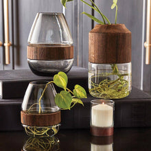 Load image into Gallery viewer, Set of four glass vases with wooden bases on a reflective surface.