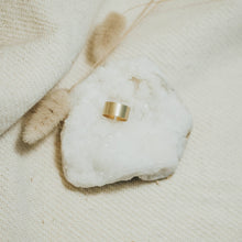 Load image into Gallery viewer, Gold ring on a white stone with a natural background