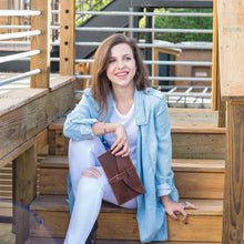Load image into Gallery viewer, Woman sitting on wooden steps holding a brown leather clutch