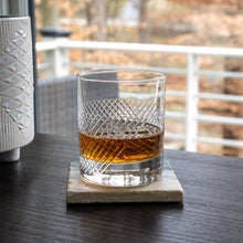 Load image into Gallery viewer, Glass of whiskey on a coaster with a blurred outdoor background