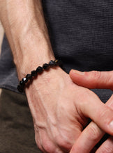 Load image into Gallery viewer, Close-up of a hand wearing a black beaded bracelet against a neutral background