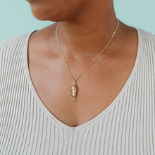 Load image into Gallery viewer, Person wearing a gold necklace with a fish pendant against a light blue background
