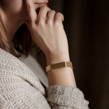 Load image into Gallery viewer, Close-up of a person wearing a gold bracelet with a blurred background