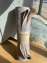 Load image into Gallery viewer, Rolled-up towel with a label on a wooden surface