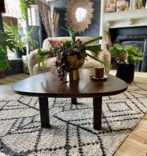 Load image into Gallery viewer, Living room with a dark wooden coffee table, decorative plants, and a patterned rug.