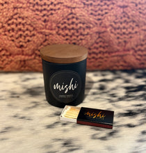 Load image into Gallery viewer, Black candle with wooden lid and matchbox on cow hide surface