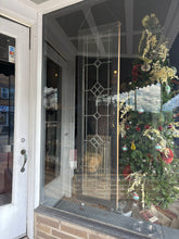 Load image into Gallery viewer, Storefront with a Christmas tree and decorations inside, reflected in the glass door.