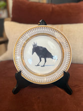 Load image into Gallery viewer, Crowned Gold plate with Crow design on a black stand on a burnt orange and tan background