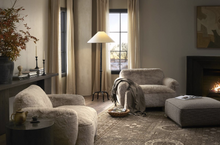 Load image into Gallery viewer, Cozy living room with plush armchairs, a lamp, and a fireplace.