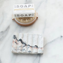 Load image into Gallery viewer, Bar of soap with a brush and packaging on a marble surface