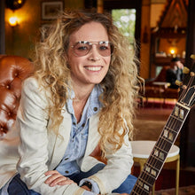 Load image into Gallery viewer, Woman with sunglasses holding a guitar in a cozy indoor setting