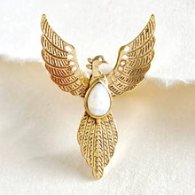 Load image into Gallery viewer, Gold angel wing ring with a white central stone on a textured beige background