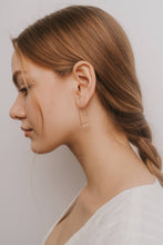 Load image into Gallery viewer, Woman with a side ponytail wearing a delicate earring against a plain background