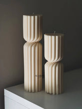 Load image into Gallery viewer, Two ribbed candles on a white surface with a dark background
