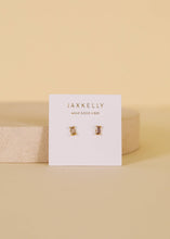 Load image into Gallery viewer, Gold earrings on a Jaxkelly branded card with a beige background