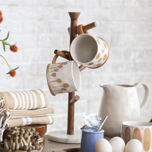 Load image into Gallery viewer, Ceramic mugs with brown speckles on a wooden stand, with a pitcher and eggs in the background.