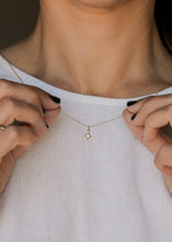 Load image into Gallery viewer, Person adjusting a delicate gold necklace with a star pendant.