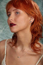 Load image into Gallery viewer, Woman with red hair and dark lipstick against a textured green background