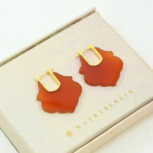 Load image into Gallery viewer, Pair of orange earrings with gold hooks on a beige box with 'NOYRE BERLIN' branding.