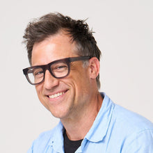 Load image into Gallery viewer, Man wearing glasses and a light blue shirt against a plain background
