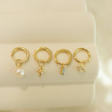 Load image into Gallery viewer, Four small hoop earrings with charms on a beige background