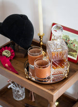 Load image into Gallery viewer, Two glasses warpped in brown leather on a tray with a crystal decanter, candle, and decorative items on a wooden surface.