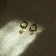 Load image into Gallery viewer, Two small hoop earrings with charms on a textured background