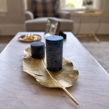 Load image into Gallery viewer, Two dark blue candles on a gold leaf-shaped tray in a living room setting.