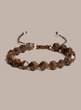 Load image into Gallery viewer, A handmade beaded bracelet featuring faceted brown gemstone beads and a braided cord with small metallic spacer beads, displayed on a solid beige background.