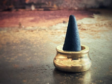 Load image into Gallery viewer, Black cone-shaped incense in a brass holder on a rustic surface