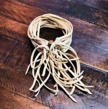 Load image into Gallery viewer, A ivory deerskin leather cuff bracelet with an antique-brass, magnetic sliding clasp, displayed on a wooden surface.