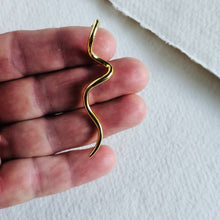 Load image into Gallery viewer, Gold snake-shaped earring held between fingers on a white background
