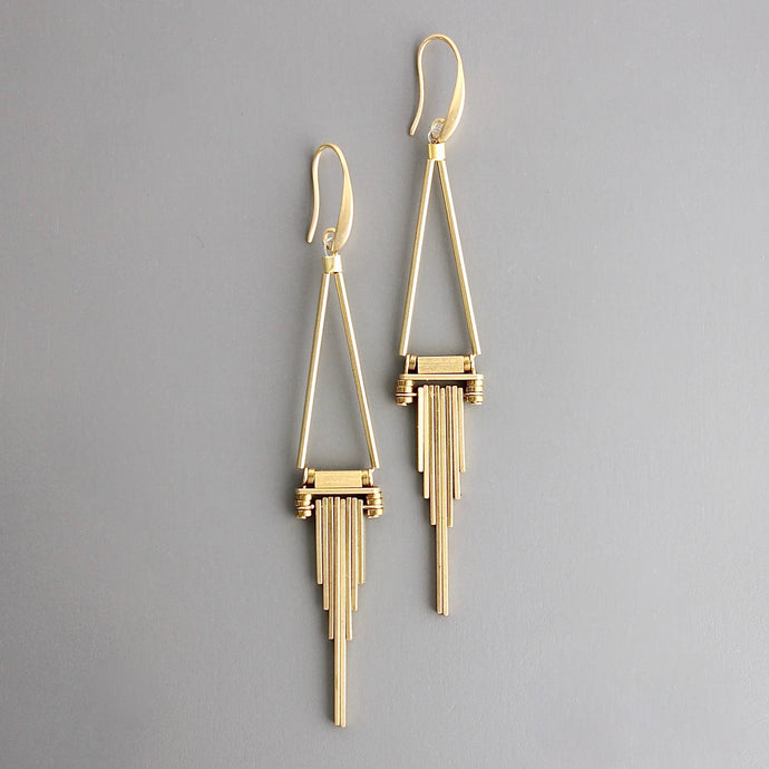 Brass dangle earrings with geometric design on a greay background