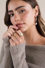 Load image into Gallery viewer, Woman wearing gold hoop earrings and rings, with a neutral background
