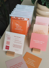 Load image into Gallery viewer, Stacks of affirmation cards on a surface with a plant in the background
